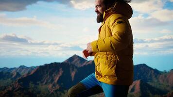 Young traveler struggling with cold winds on top of the mountain, feeling proud of his trekking activity. Adventure seeker with ambition successfully climbing the mountain range. Camera A. video