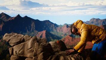 Foolish hiker tripping and losing balance on the rocky mountain peak, struggling to climb unequipped in the extreme wilderness. Dangerous landscape for an unprepared explorer. Camera B. video