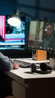 Vertical Black remote worker meeting with his team leader via conference call, sharing ideas and insight on his tasks from his home office setup. Young adult joining web chat with boss. Camera B. video