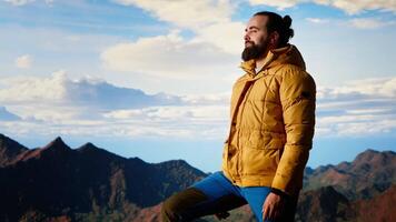 Peaceful pleased traveler feeling happy climbing the mountain, enjoying mindfulness and determination. Young man being passionate about the wilderness and the scenic view. Camera B. video