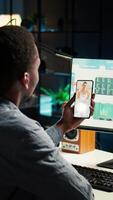 Vertical Black remote worker meeting with his team leader via conference call, sharing ideas and insight on his tasks from his home office setup. Young adult joining web chat with boss. Camera A. video