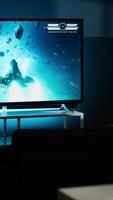 Vertical Guy spends time on television playing multiplayer web games, setting his console into smart tv and having fun gaming at night. Player battling in shooter competition. Camera B. video