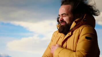 Young traveler struggling with cold winds on top of the mountain, feeling proud of his trekking activity. Adventure seeker with ambition successfully climbing the mountain range. Camera B. video