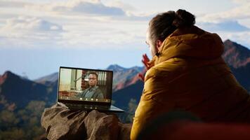 Young CEO entering a call from the mountain top with a strong signal, always connected and discussing with associates about business matters. Workaholic man hiking. Camera B. video