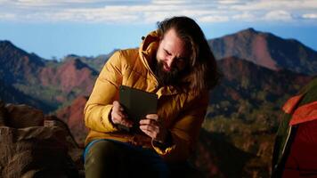 Tech dependent hiker ignores the beauty of nature and works online at a windy campsite, entering his tent to be safe from the wind and cold weather. Dangers of technology addiction. Camera B. video
