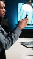 Vertical Independent adult teleworking from home and using his mobile phone, navigating social media and answering emails before starting his daily tasks completion. Comfortable modern setup. Camera B. video