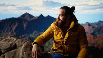Trekker climbing to the top of a breathtaking mountain range and soaks in the stunning scenery while he rests. Feeling proud of his personal achievement as a nature lover. Camera A. video