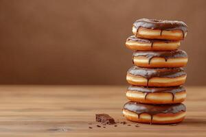 Stack of chocolate glazed donuts on a wooden table photo