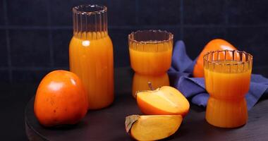 Fresh persimmon juice displayed on wooden table video