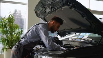 Car mechanic inspecting engine under open hood in workshop with lamp video