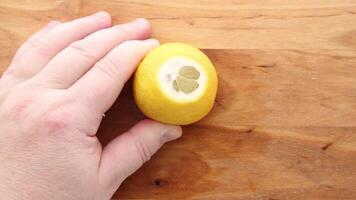 A lemon being squeezed by hand over a wooden surface, extracting fresh juice. video