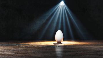 A single white egg stands alone on a wooden surface, illuminated by a beam of light from above, creating a unique atmosphere of suspense and intrigue. video