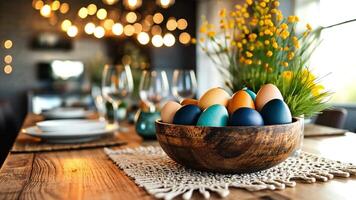 A bowl filled with vibrant, decorated eggs sits on a rustic table surrounded by elegant dishware and glasses, illuminated by warm, ambient lights. video