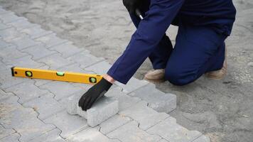Worker installing paving stones with mallet and level tool video