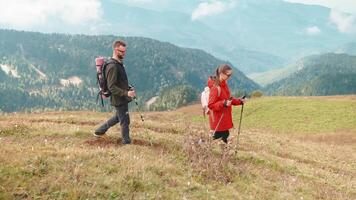 People hikers tourists walking in mountains with sticks in hands on slope. video