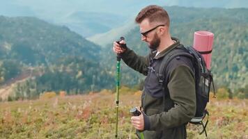 Hiker tourist man go down mountain slope on narrow path with sticks in hands. video