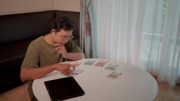 Man counting money. A man sits at a table, meticulously counting bills, showcasing the delicate dance between finances and responsibility. video