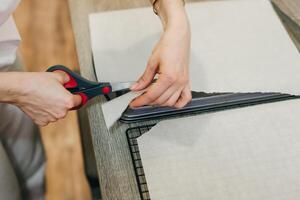 Hand holding up a sheet of baking paper and cut using a pair of scissors, photo