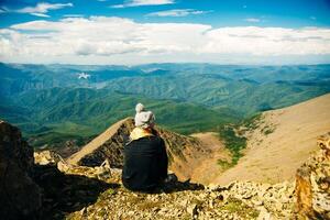 The girl sits and admires the beautiful mountain view photo