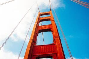 Close up of single tower of Golden Gate Bridge in white clouds San Francisco, USA, bottom view.. photo