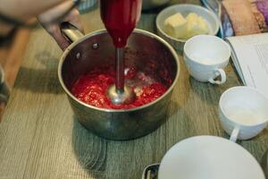 Whipping strawberry buttercream frosting in a stand-alone electric mixer with a whisk attachment.. photo