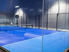 Under a vast modern structure, newly installed padel courts. Centered is the entrance to the courts, on one side, photo