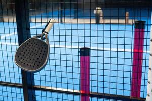 Padel Racket Strung in the Outdoor Structure Surrounding the Playing Field and Players in the Background. photo