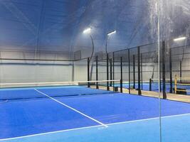 Under a vast modern structure, newly installed padel courts. Centered is the entrance to the courts, on one side, photo