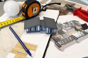 Architects house model with measurement tool and blueprints on architect desk. A architects home model with plan and blueprints. Business, architecture, building and construction concept. photo