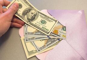 Envelope with dollars on a wooden background. Dollars in a envelope. photo