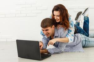 Dreamy couple lying on floor in empty room and looking up, imagine future interior design project, white background. photo