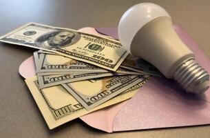 Energy saving light bulbs with american currency , dollars on a background. Payment for electricity, financial condition of the energy market, increase in energy prices. photo