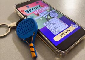 smartphone with application for sport bets and a padel racket, concept of online bets photo