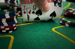 Close Up Shot On Hand Of Anonymous Poker Player Checking Playing Cards He Was Dealt. Professional High Stakes Gambler Making A Bet, Thinking Of Strategy, Counting Chips In Competitive Tournament. photo