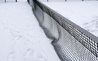 Row of snow covered tennis court nets, in a weather delay concept, with space for text photo