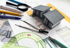 Architects house model with measurement tool and blueprints on architect desk. A architects home model with plan and blueprints. Business, architecture, building and construction concept. photo