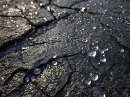 A macro photograph highlighting snowflakes slowly dissolving on an uneven asphalt surface. photo
