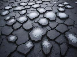 A crisp close-up of snowflakes dissolving on the rough, gritty texture of asphalt. photo