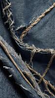 A close-up capture of distressed denim fabric with visible thread fraying. photo