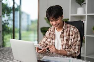 Young man using smartphone while reviewing financial statements at home. photo