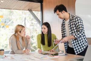 Diverse team deep in discussion while analyzing design materials in an office. photo