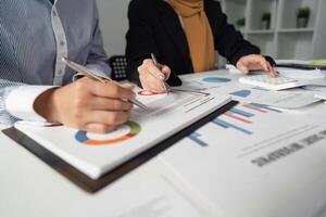 Financial analysts reviewing tax documents and data visualization in a collaborative office setting. photo