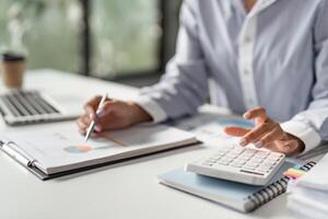 Finance worker calculating data with a calculator and reviewing reports in a modern office. photo