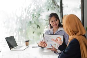 Female finance workers presenting financial data and discussing reports in an office. photo