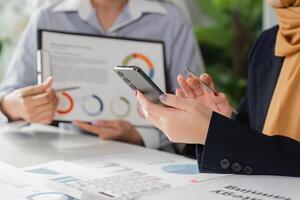 Diverse professionals analyzing financial reports and using a smartphone for strategy planning in the office. photo