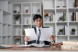 Young professional in suit reviewing documents at desk, analyzing information and making decisions in modern office. photo