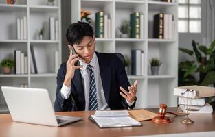 Young businessman discussing important matters on the phone while reviewing documents in a modern office. photo
