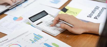 Office worker calculating financial data with charts and a calculator, focusing on budget planning. photo