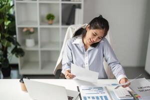 Finance worker reviewing documents while on a phone call in a contemporary office. photo