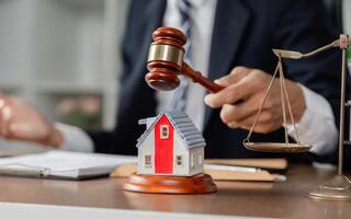 Lawyer using gavel to signify decision on property case with model house and scales of justice. photo
